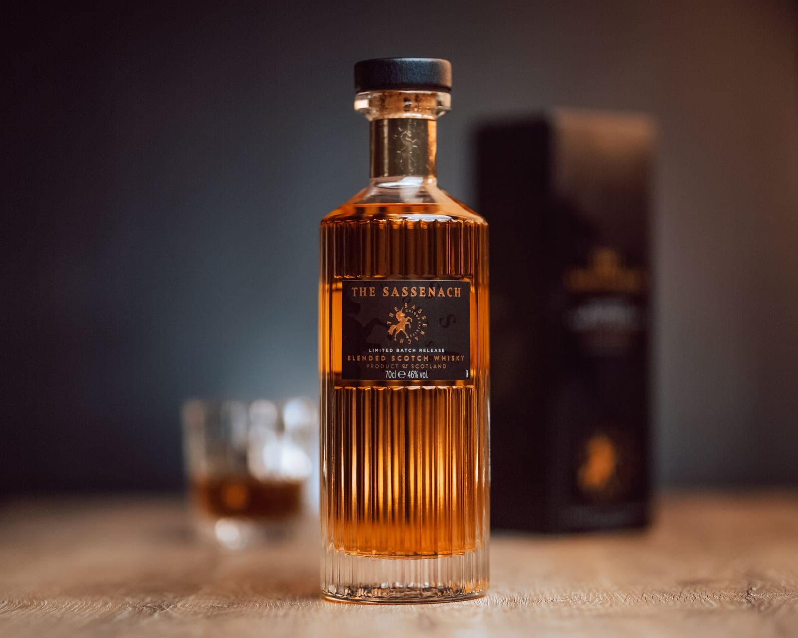 A whiskey bottle beside a wrapped gift box