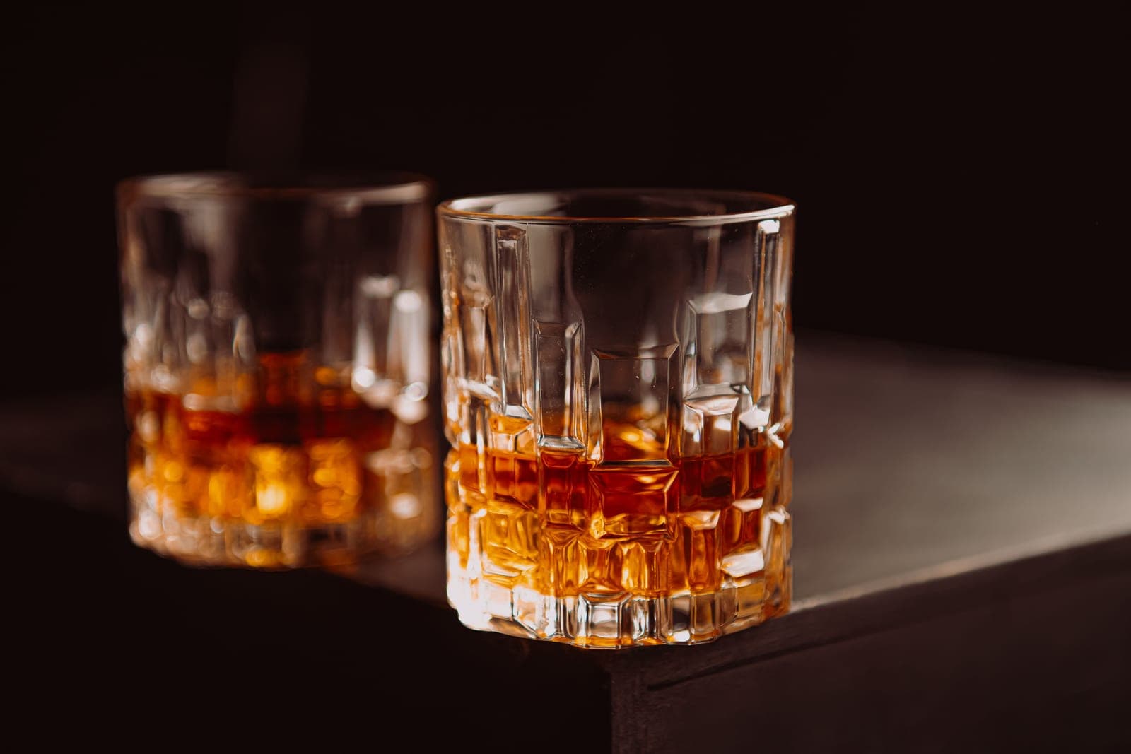 A glass of whiskey on a wooden table in warm afternoon light